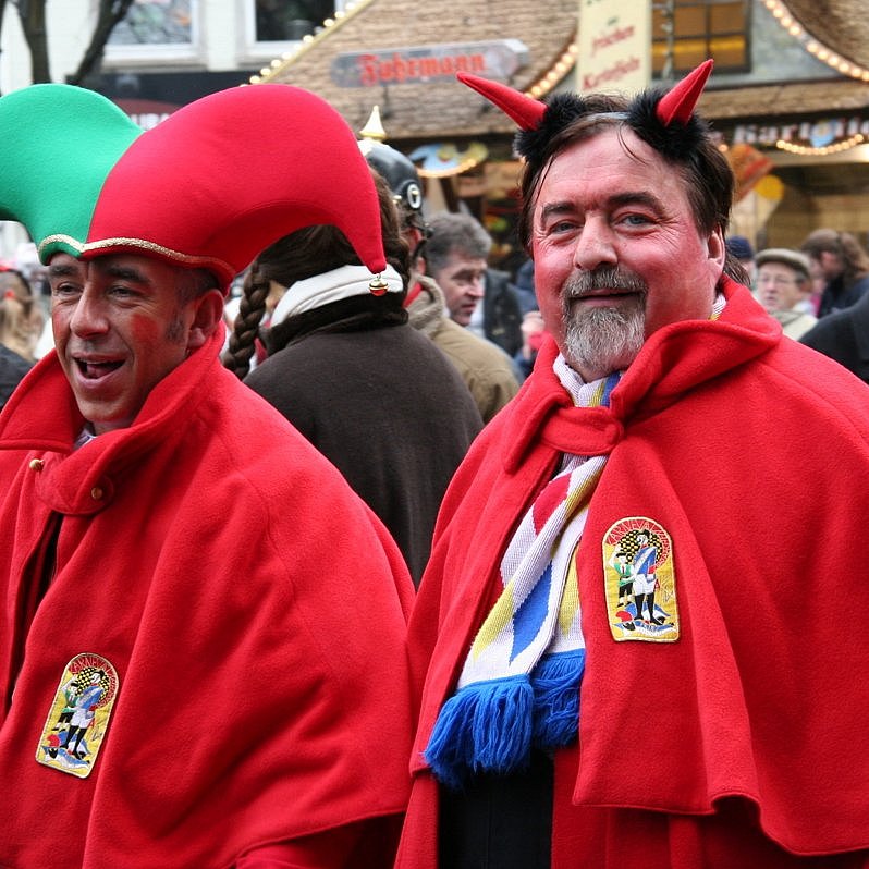 Zwei Personen im Straßenkarneval. Eine Person mit roten Hörnern, die ihn als Teufel darstellen.