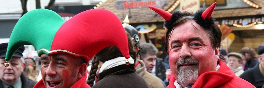 Zwei Personen im Straßenkarneval. Eine Person mit roten Hörnern, die ihn als Teufel darstellen.