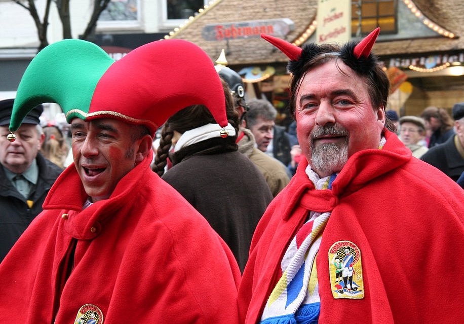 Zwei Personen im Straßenkarneval. Eine Person mit roten Hörnern, die ihn als Teufel darstellen.